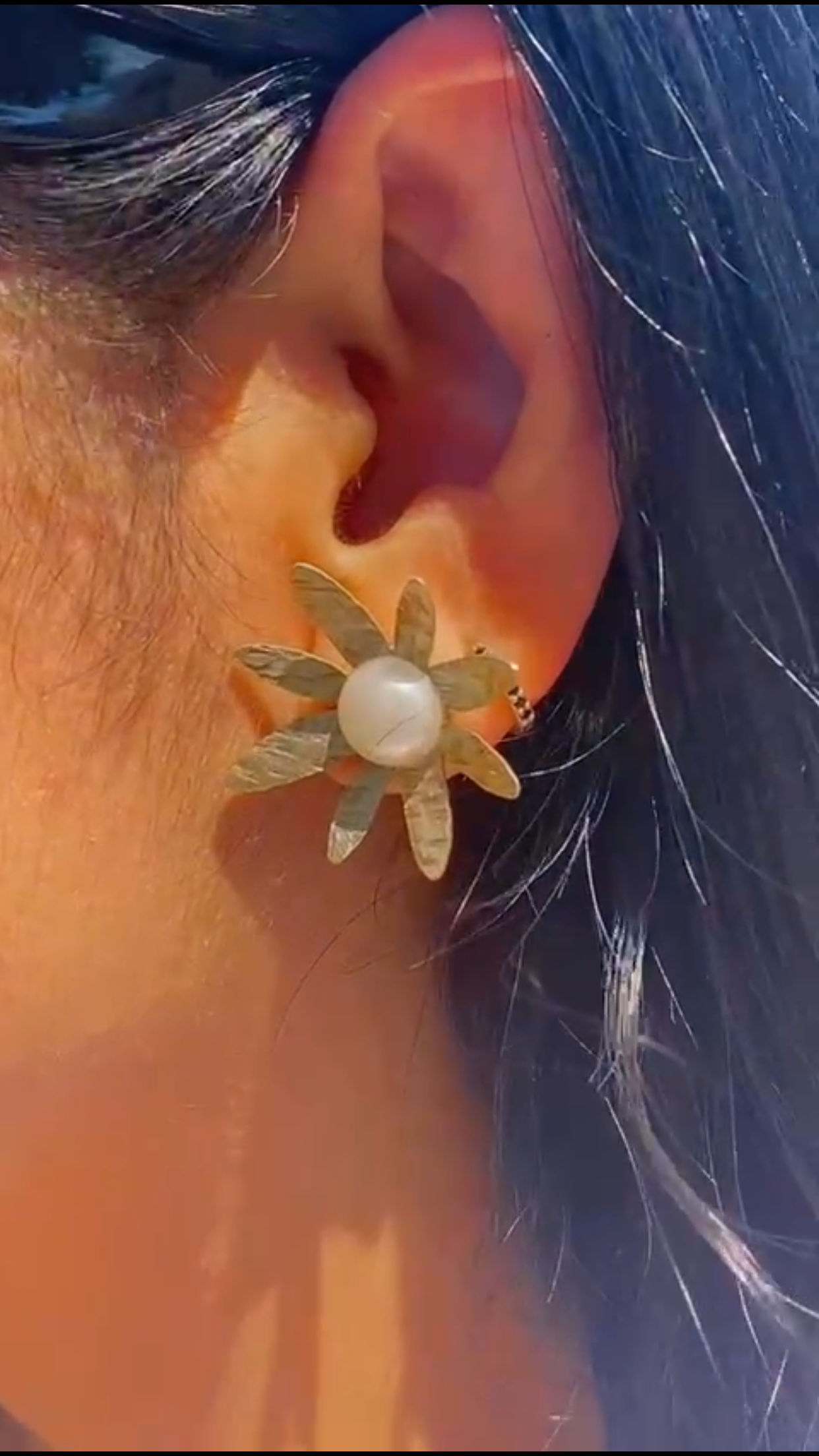 Oreja de mujer con pendientes en forma de Margaritas, hechos a mano en Latón. En nuestro taller artesanal del centro de Madrid.